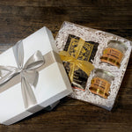 Load image into Gallery viewer, An image of a white gift box with chocolate bars and candles inside, surrounded by crinkle paper
